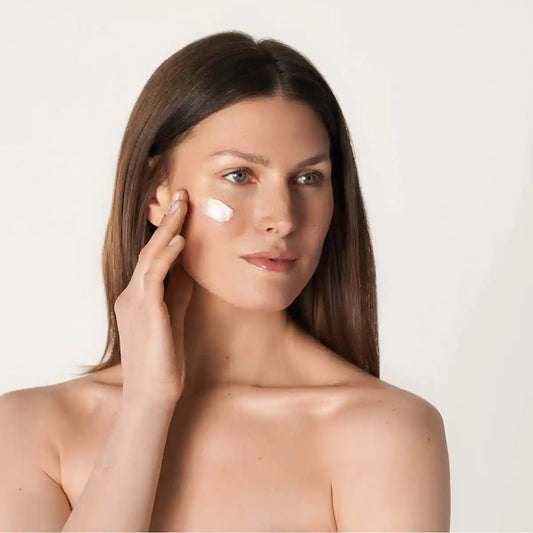 Anwendungsfoto_Frau_mit_gruenen_Augen_und_braunen_Haaren_traegt_QMS_Medicosmetic_Creme_auf